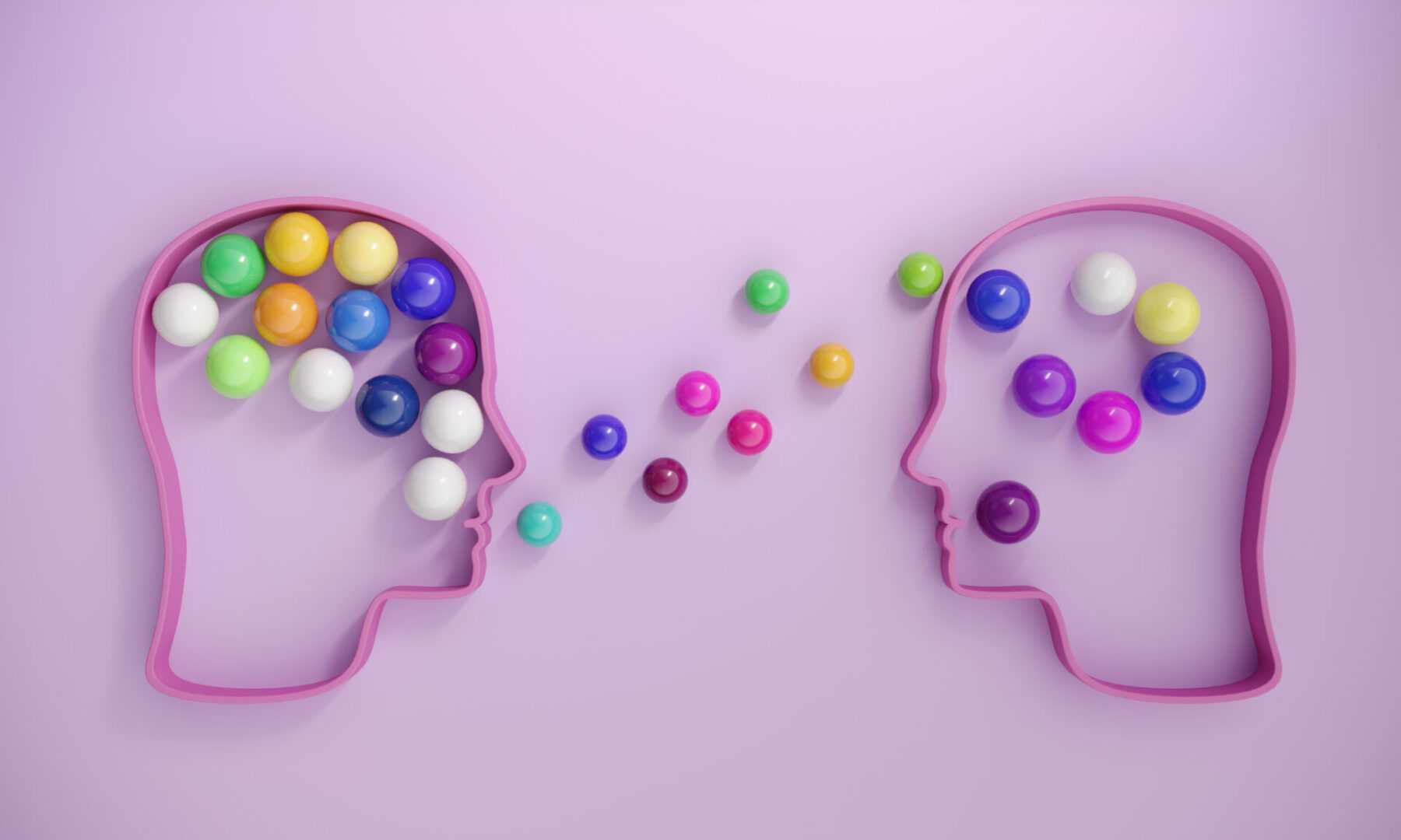 Two heads exchanging colorful balls, symbolizing communication.